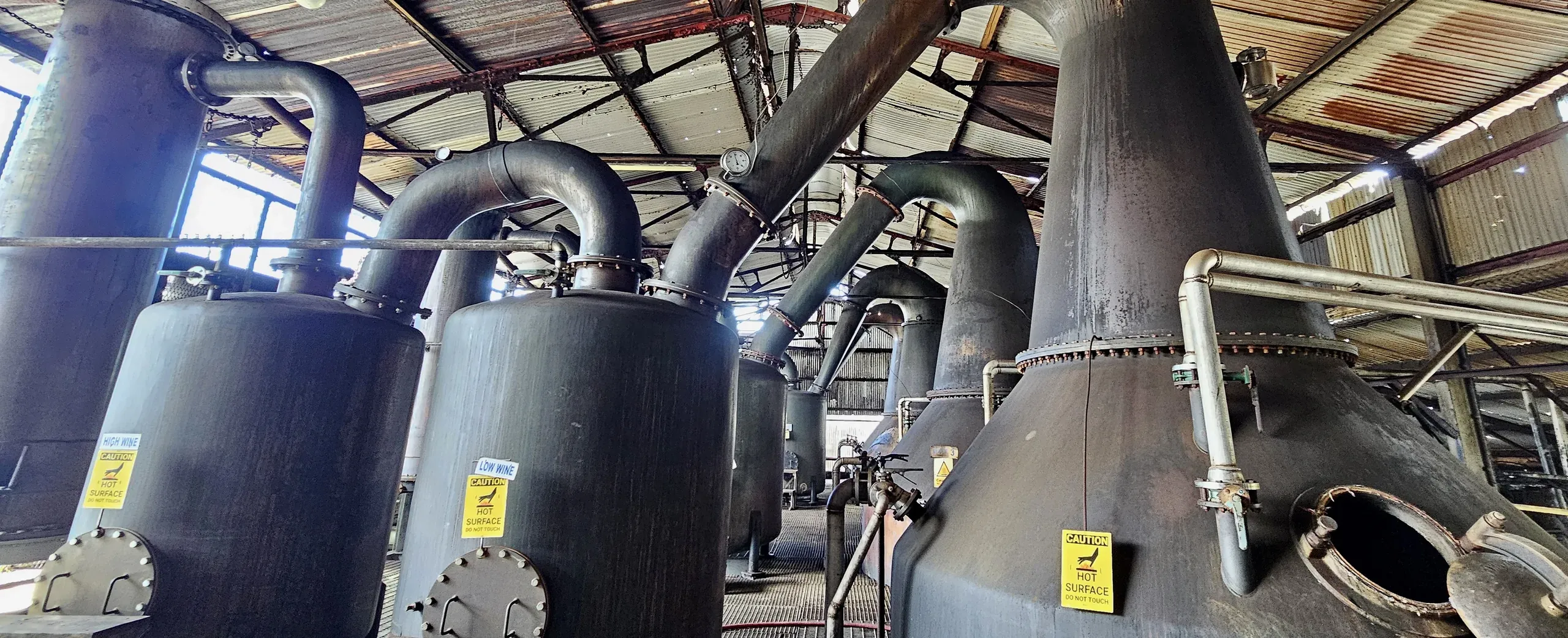 Heavy pot stills and their retorts under a corrugated roof